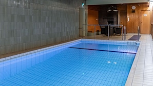 Una piscina interior con paredes de azulejos y revestimiento de madera.