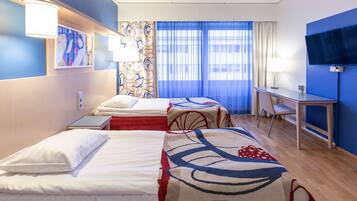Quarto de hotel com duas camas, uma mesa, uma televisão e uma janela com cortinas.