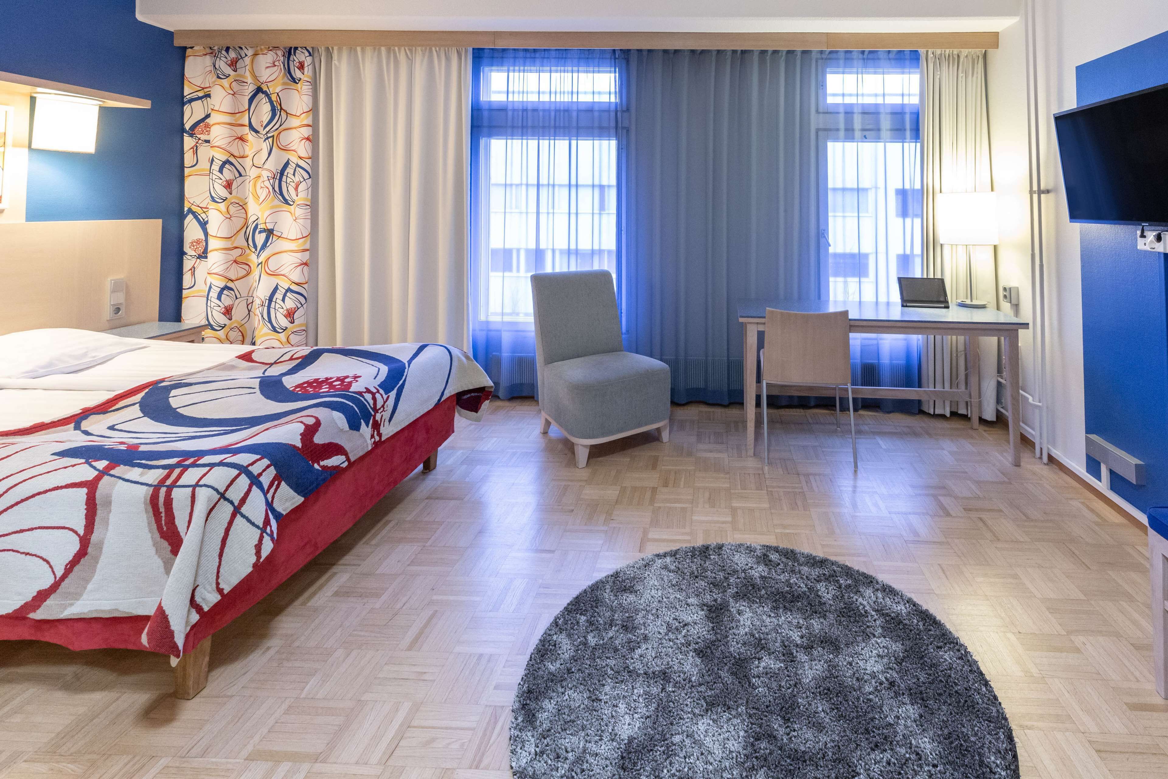 Ein Hotelzimmer mit Bett, Schreibtisch, Stuhl und Fernseher.