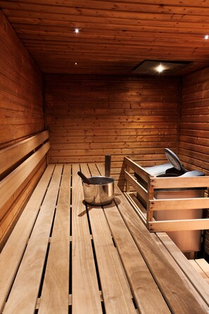 Un sauna en bois, doté de bancs et d’une baignoire à sauna.