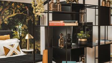A modern living room with a black bookshelf, a sofa, and a decorative plant.