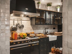 A modern kitchen with stainless steel appliances, black cabinetry, and a variety of food items displayed on the counter. - Maisons du Monde Hôtel & Suites - Marseille Vieux Port (Marseille)