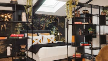 A modern bedroom with a skylight, a white bed, black and gold decor, and a bookshelf.