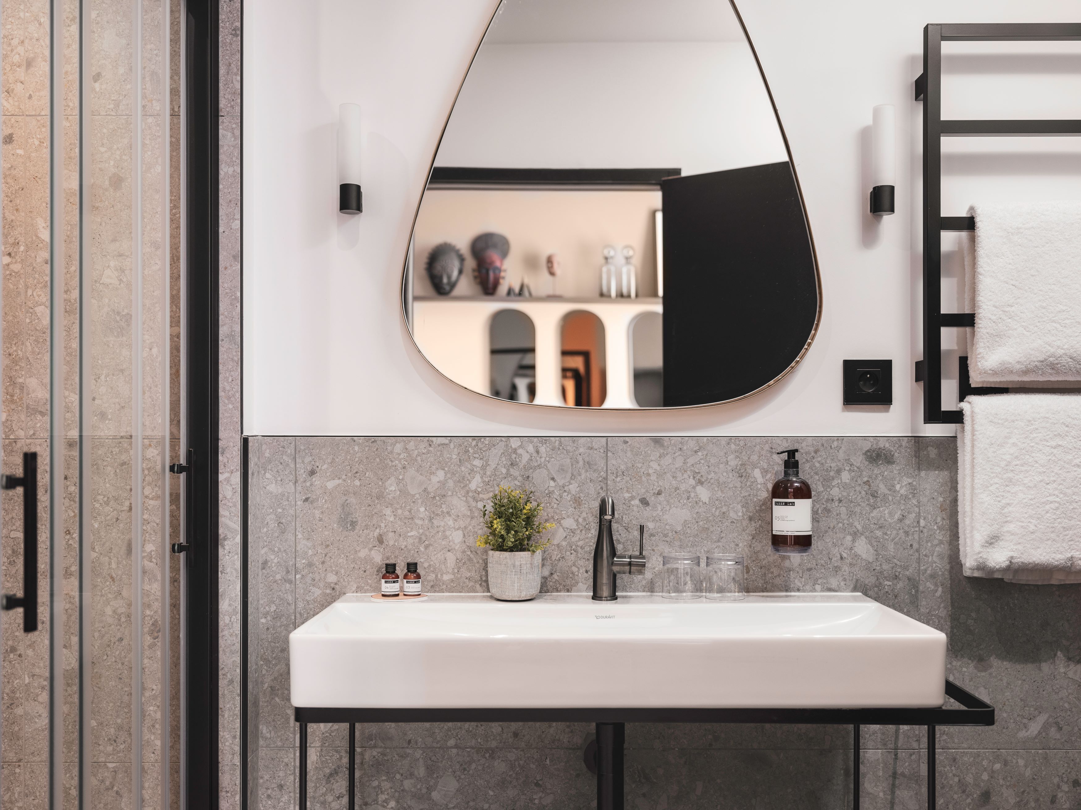 Un baño moderno con un espejo grande, un lavabo blanco y un perchero para toallas.