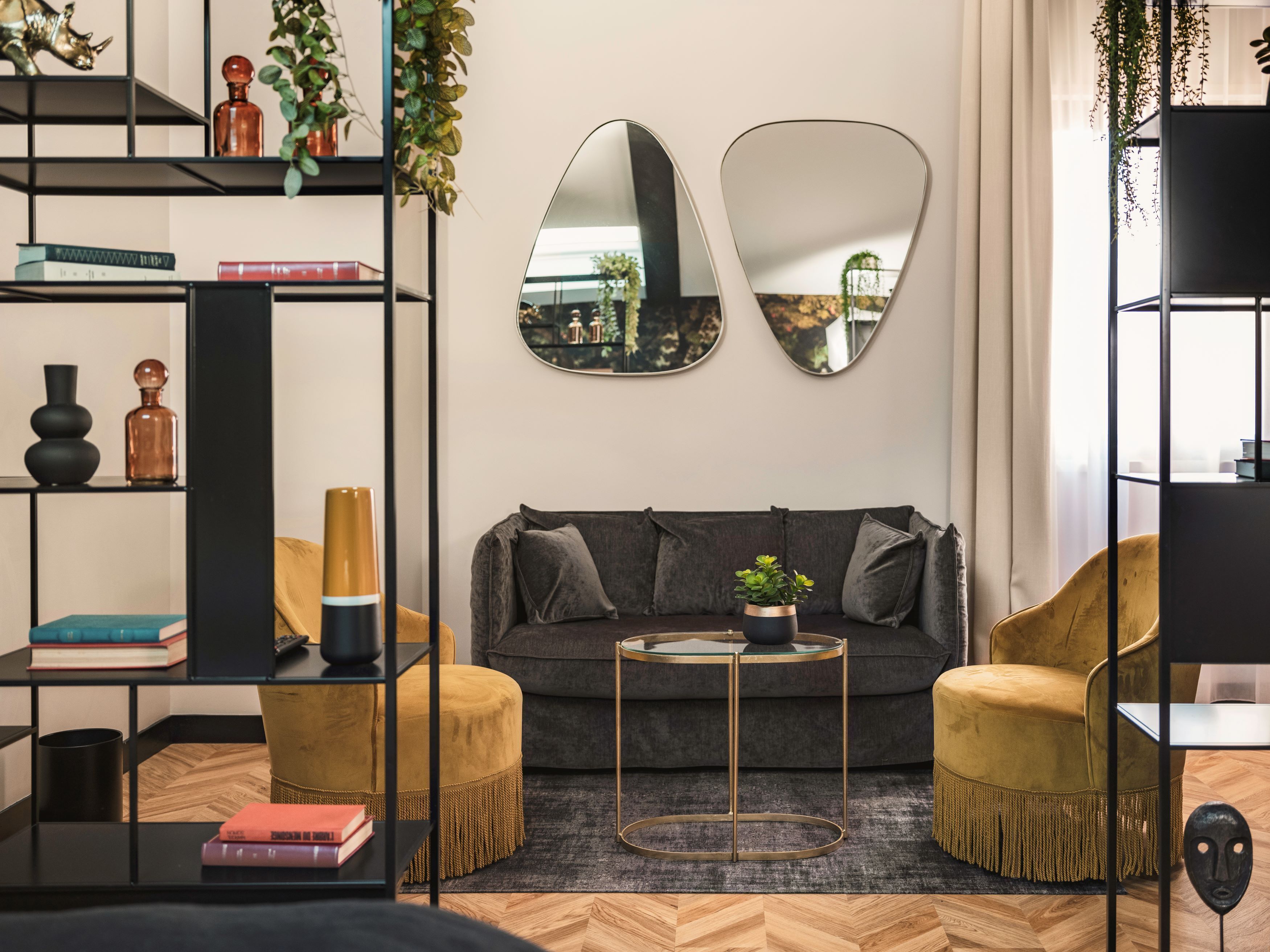 Ein modernes Wohnzimmer mit einer Couch, zwei Sesseln, einem Couchtisch und einem Bücherregal.
