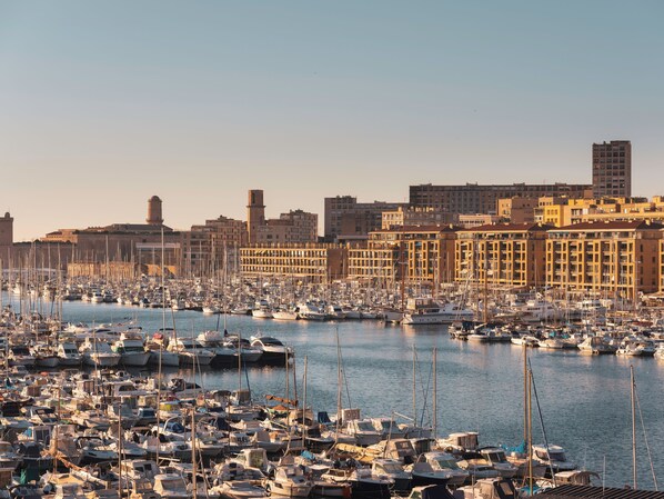 A marina filled with boats, a city skyline with historic buildings, and a clear sky.