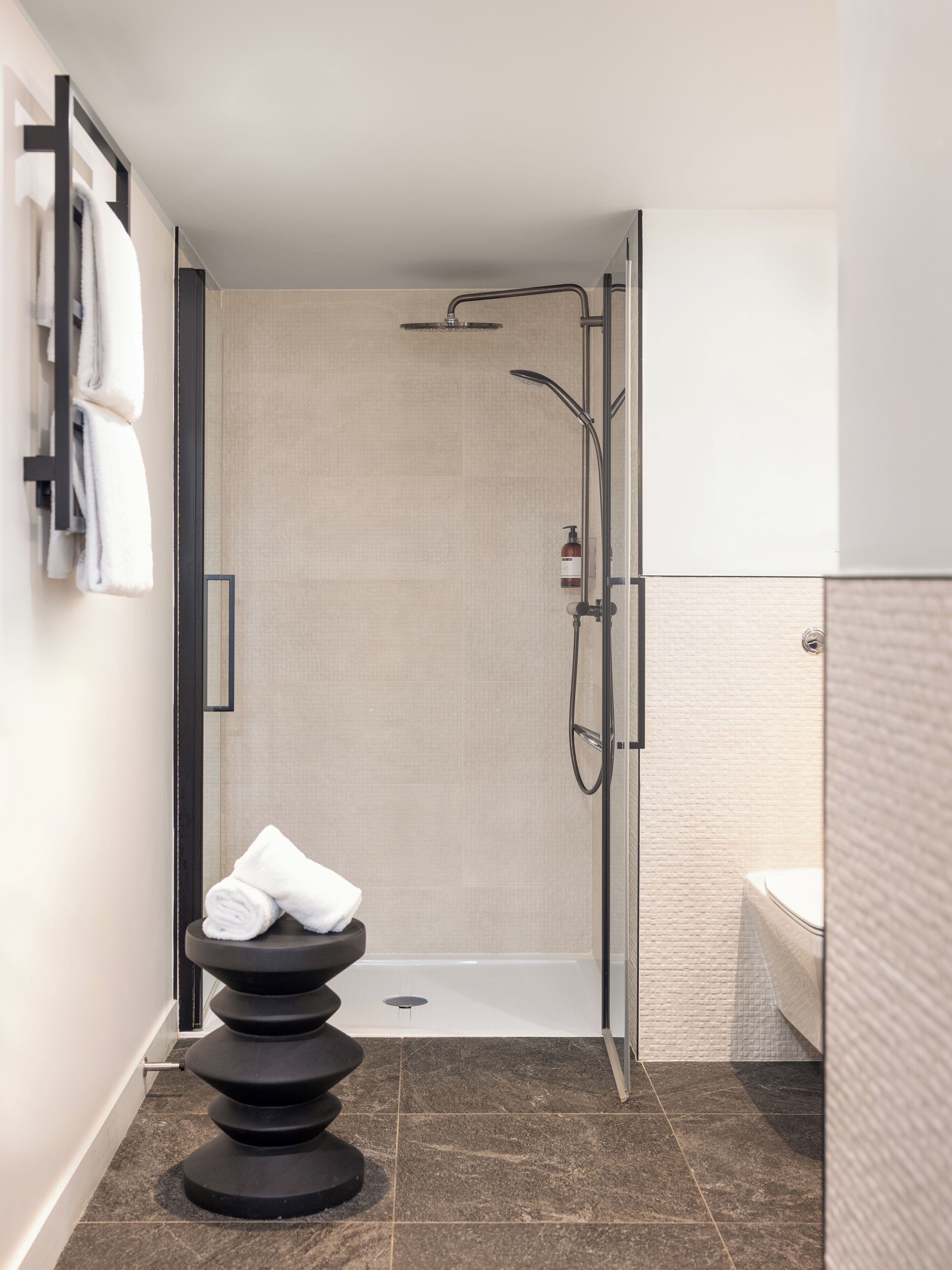 A modern bathroom with a glass-enclosed shower, a black soap dish, and a white toilet.