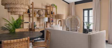 Uma sala de estar moderna com área de jantar, apresentando uma mesa redonda, cadeiras de madeira, um sofá e um grande candeeiro de fibra.