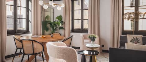 Un comedor moderno con una mesa redonda de madera, sillas de mimbre y un sillón blanco.