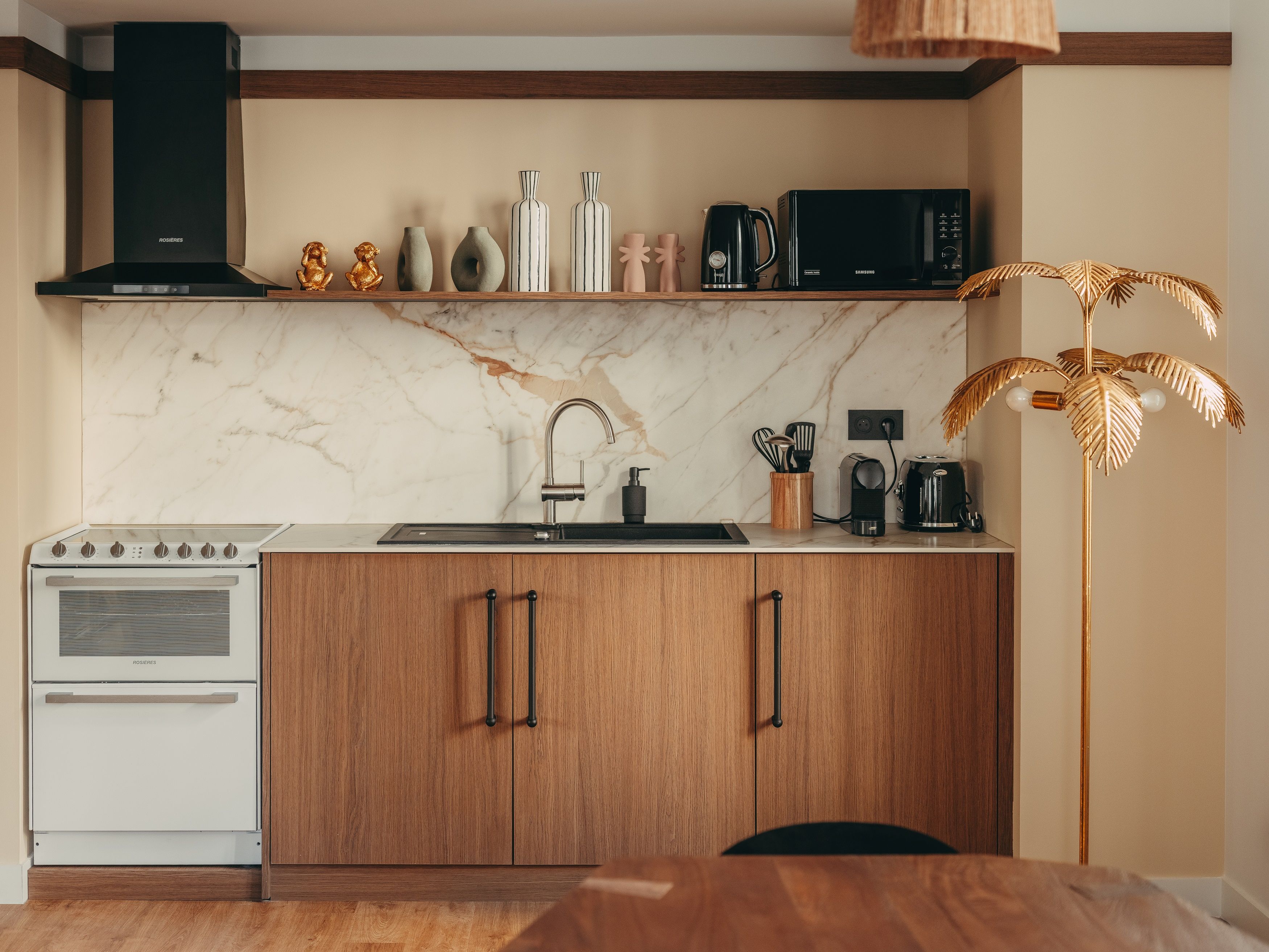 A kitchen with a white stove, wooden cabinets, a black range hood, a marble backsplash, and a wooden floor.
