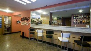 Una zona de bar con mostrador, varias sillas y un espejo.