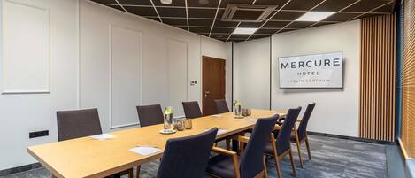 A conference room with a long table, chairs, and a sign reading 'Mercure Hotel Lublin Centrum'.