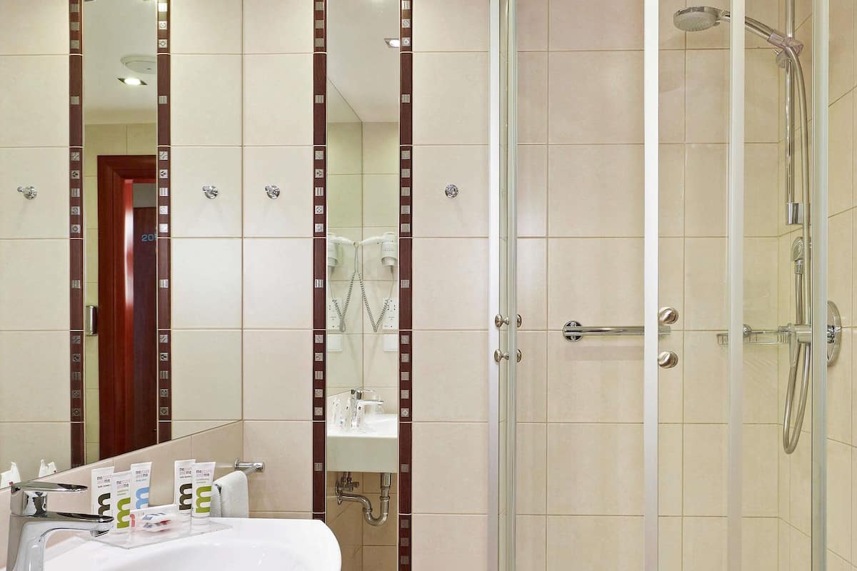 A bathroom with a sink, mirror, shower, and towel rack.