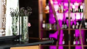 A bar area with a glass display case containing flowers and a pink flower. - Hotel Mercure Lublin Centrum (Lublin)
