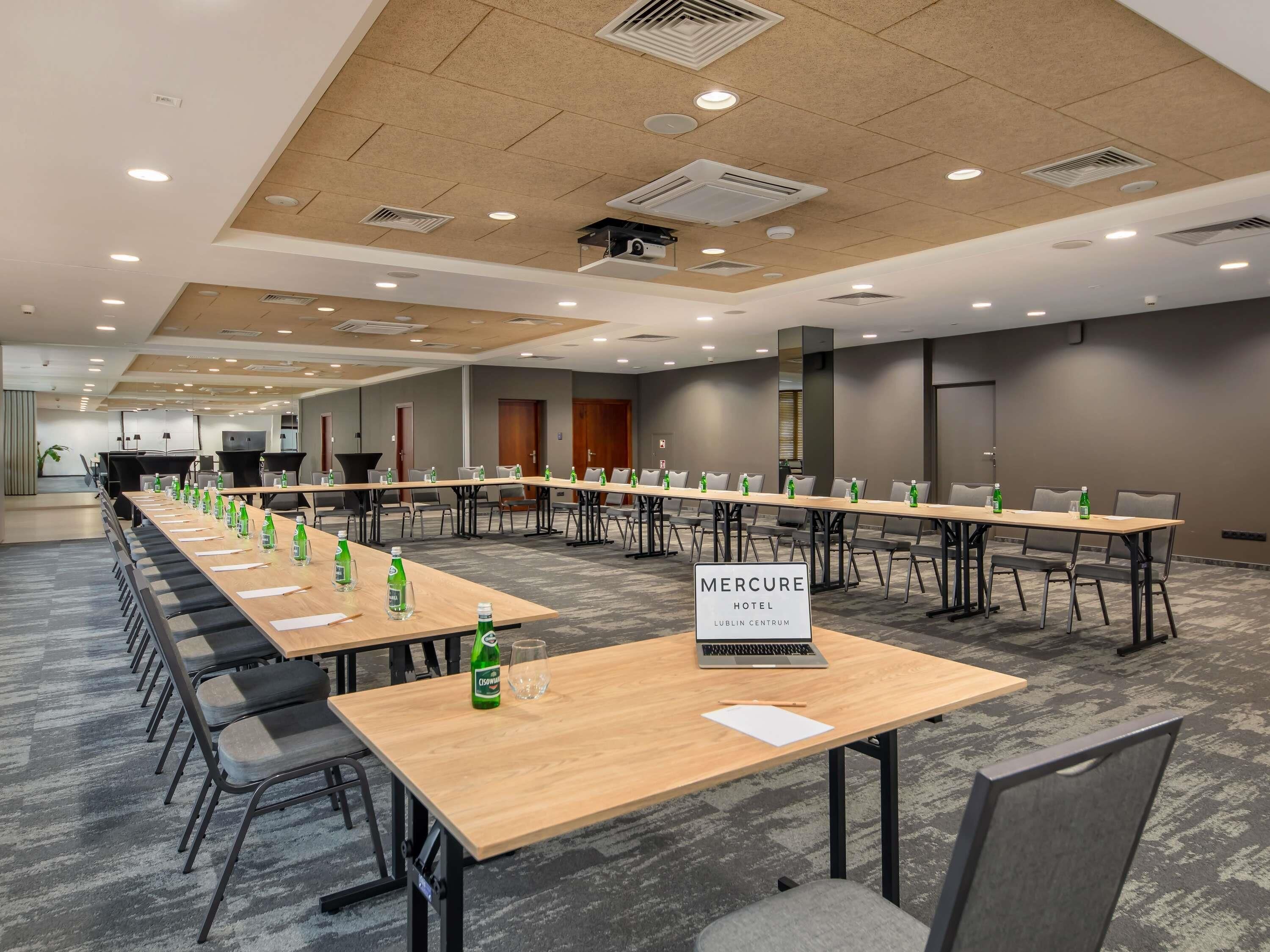 A conference room with long tables, chairs, and a sign indicating it's at Mercure Hotel in Lublin Centrum.
