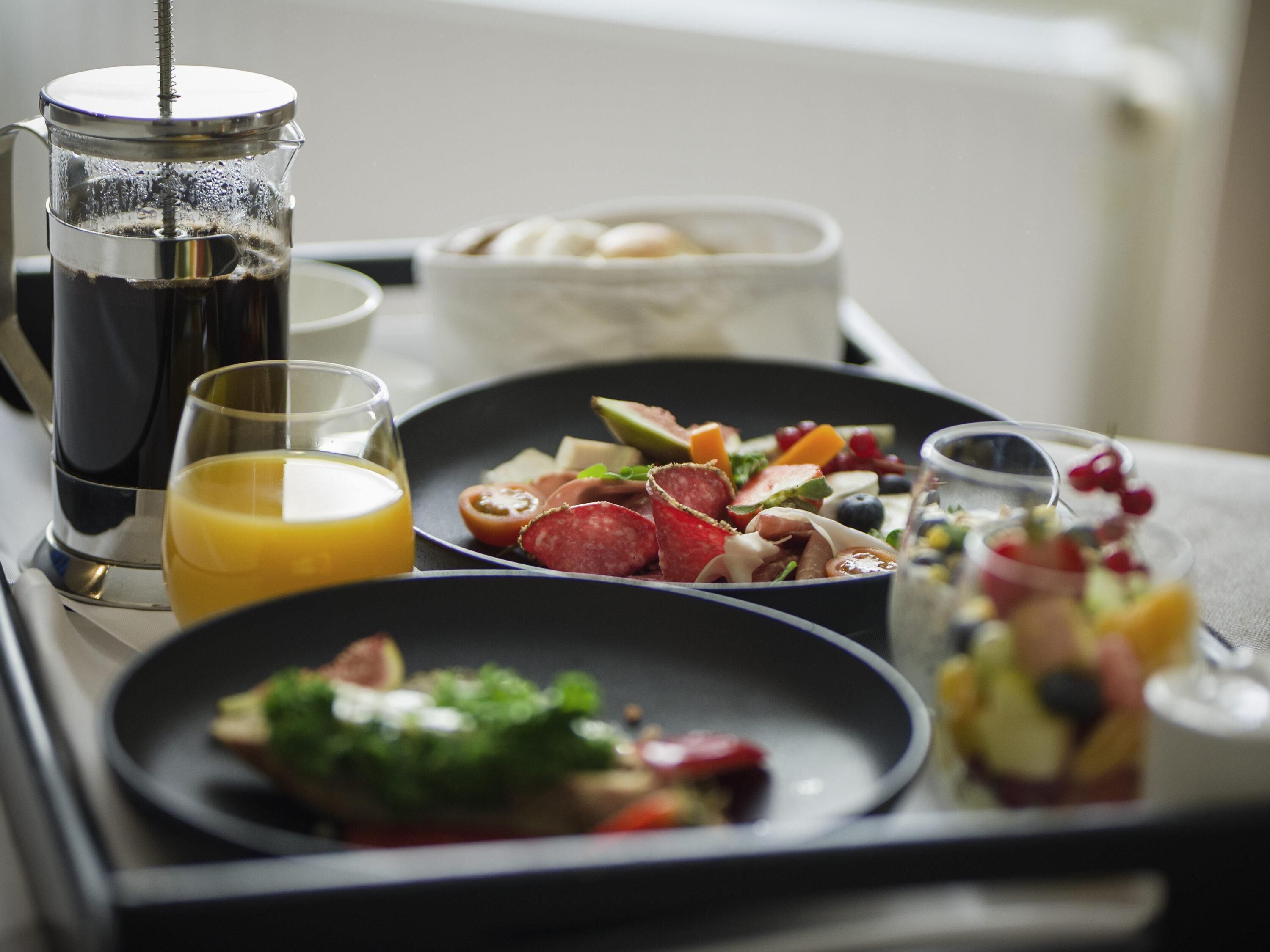 A breakfast tray with coffee, juice, and various food items.
