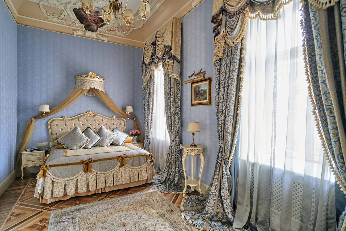Un dormitorio con una cama grande, cortinas decorativas y una araña.
