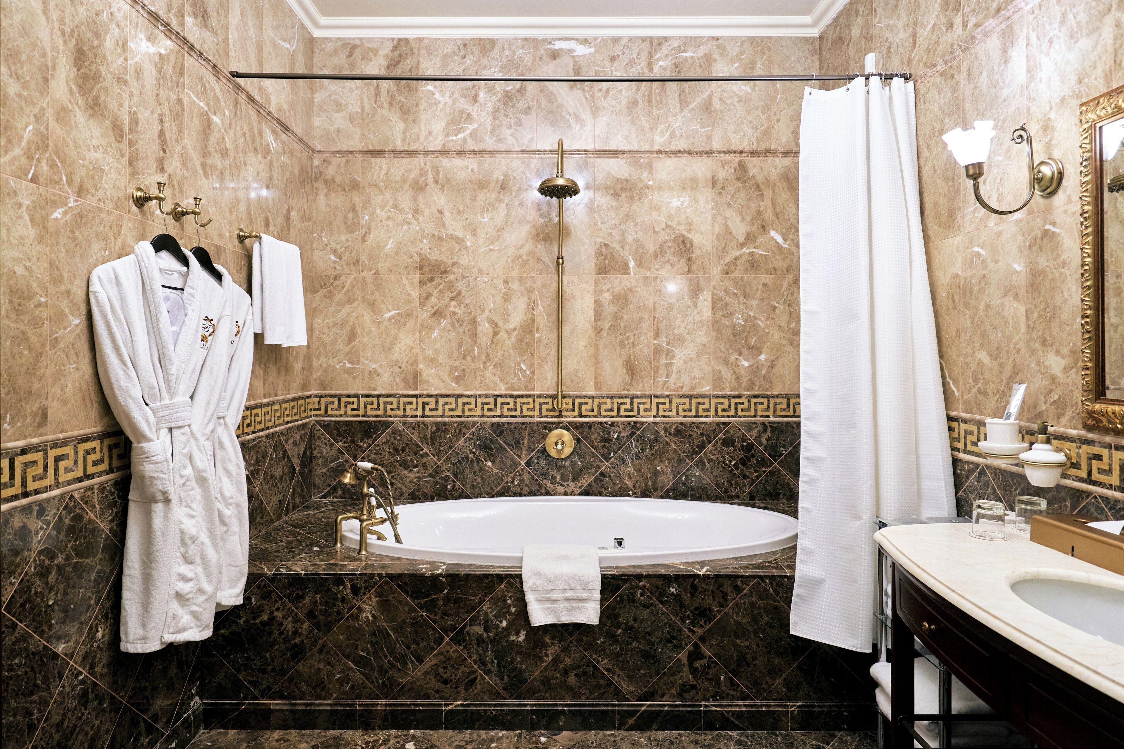 A bathroom with a bathtub, a vanity with a mirror, and a robe hanging on the wall.