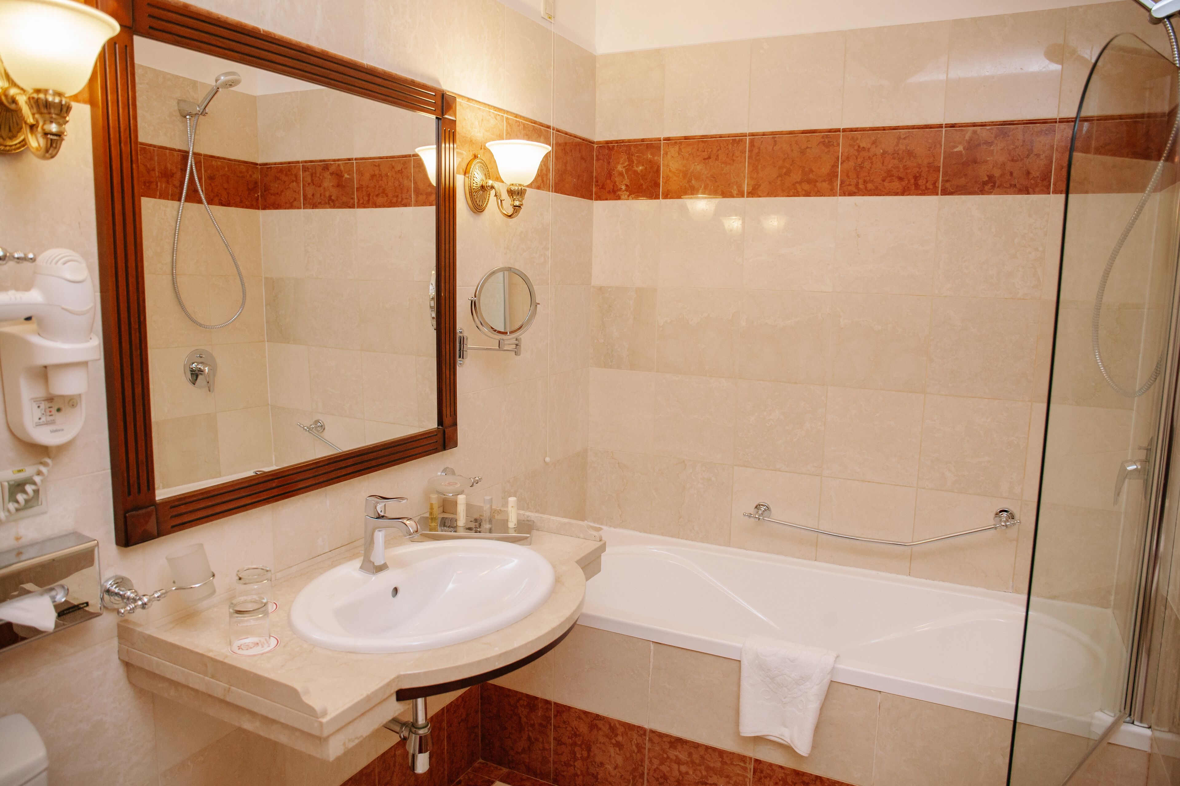 A bathroom with a sink, mirror, and bathtub.