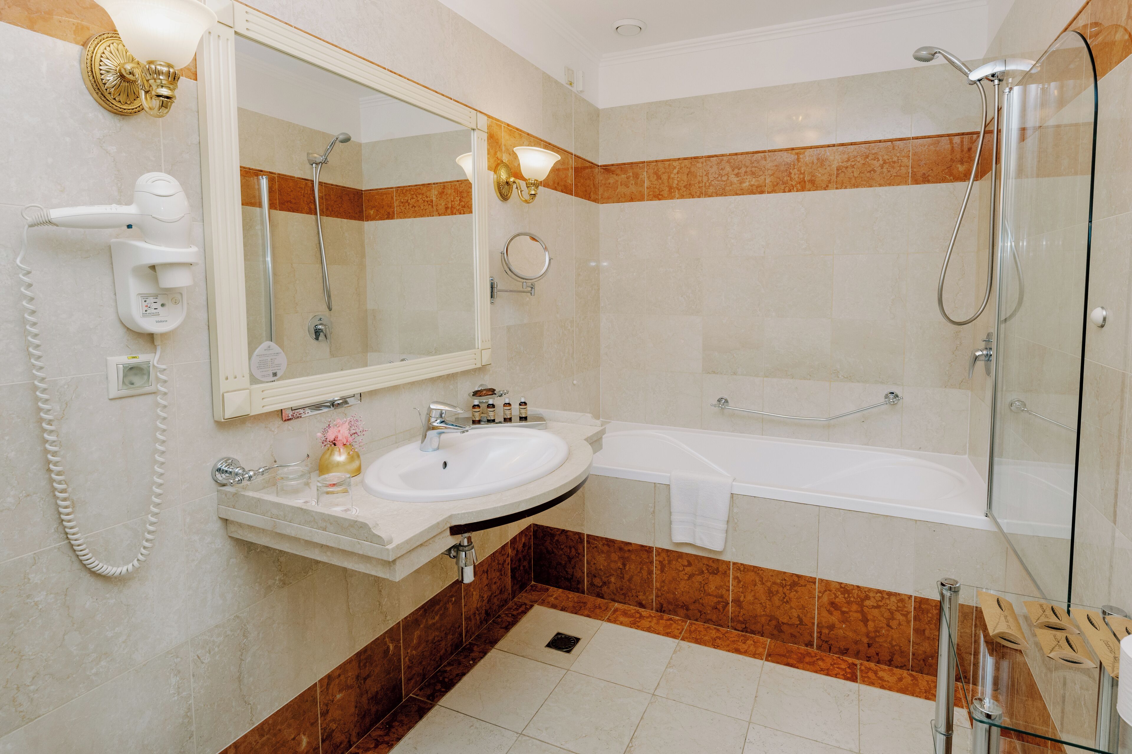A bathroom with a sink, mirror, shower, and towel rack.