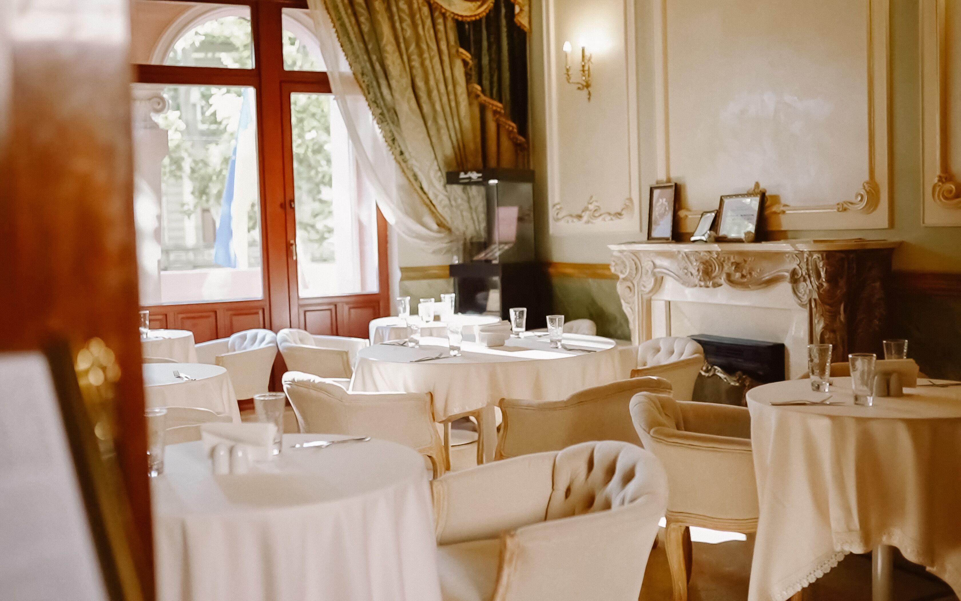 A dining area with round tables, chairs, and a fireplace.