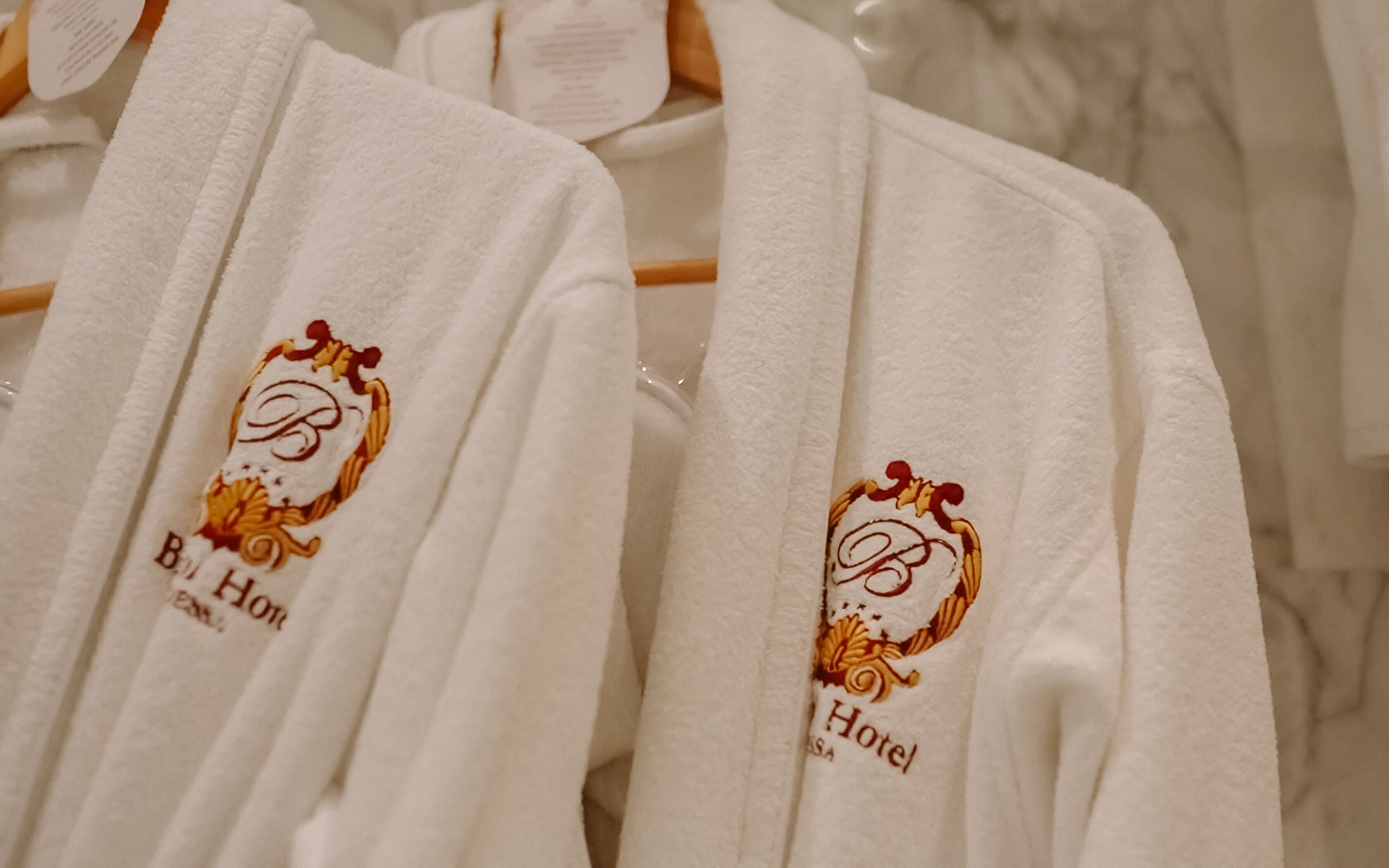 White robes with embroidered logos and text indicating they are from a hotel.