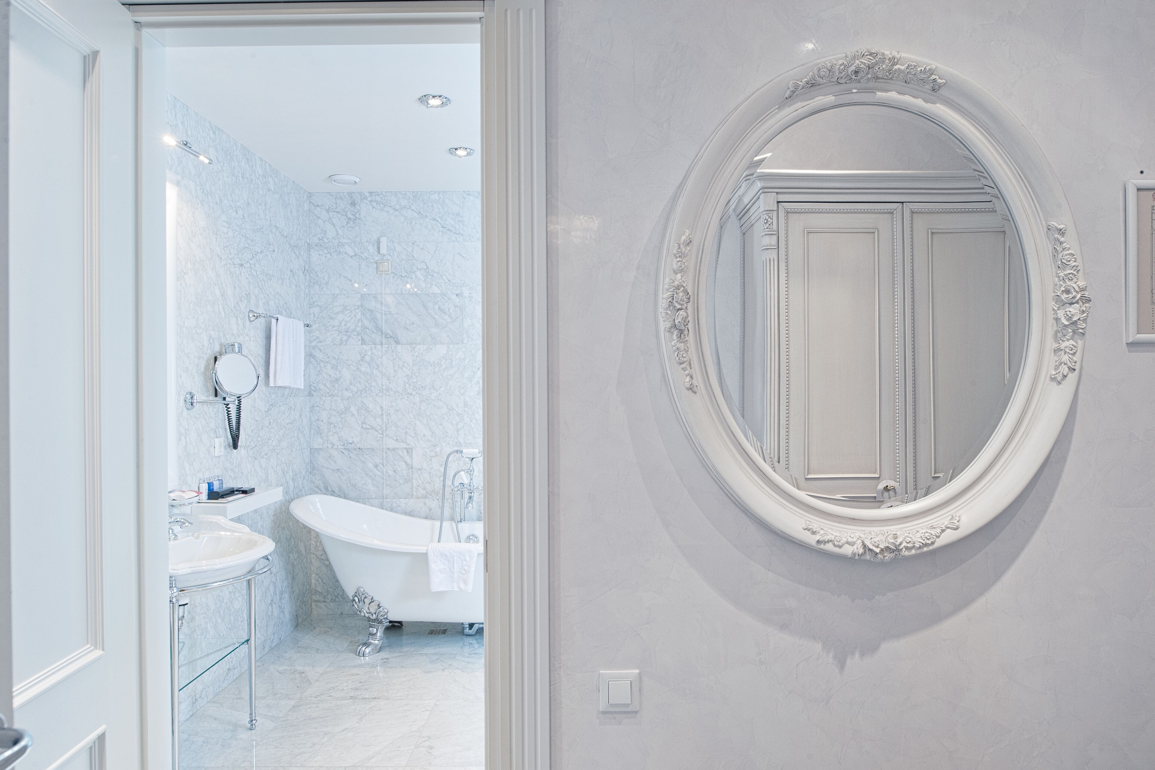Une salle de bain avec une baignoire sur pieds, un meuble-lavabo avec un miroir et des toilettes fixées au mur.