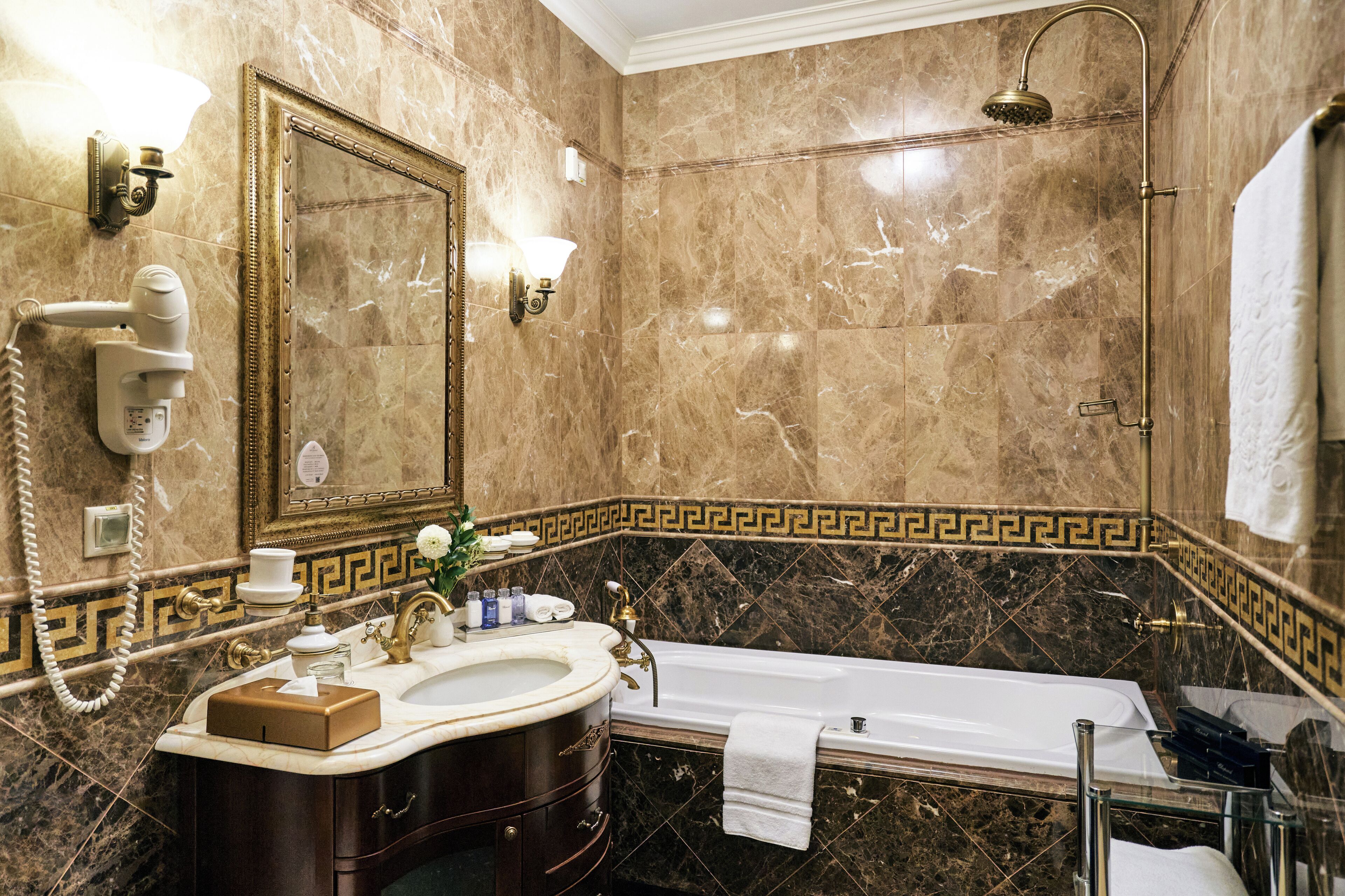 A bathroom with a marble sink, vanity, bathtub, and a shower.
