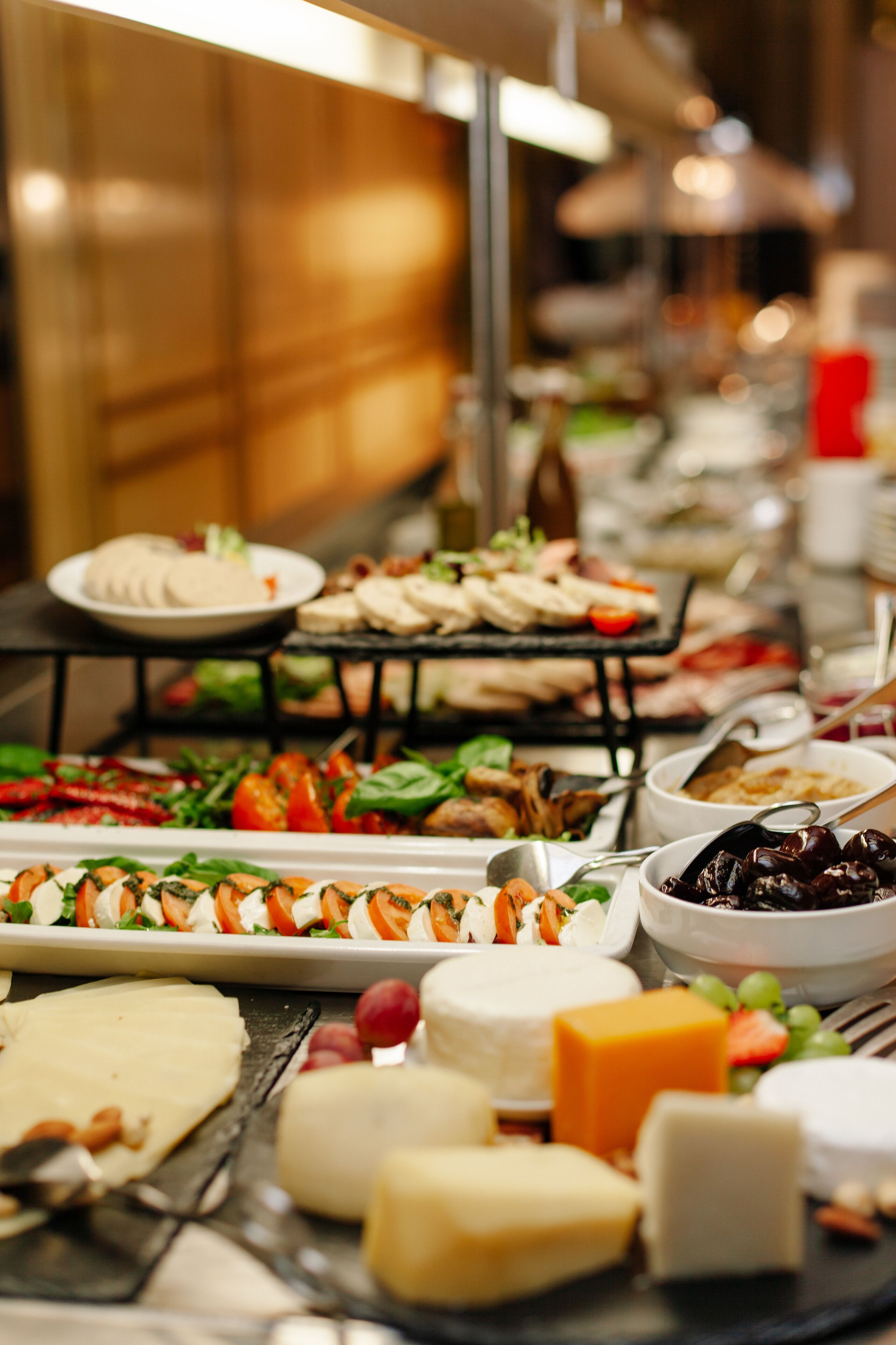 A buffet with various food items including cheeses, fruits, and salads.