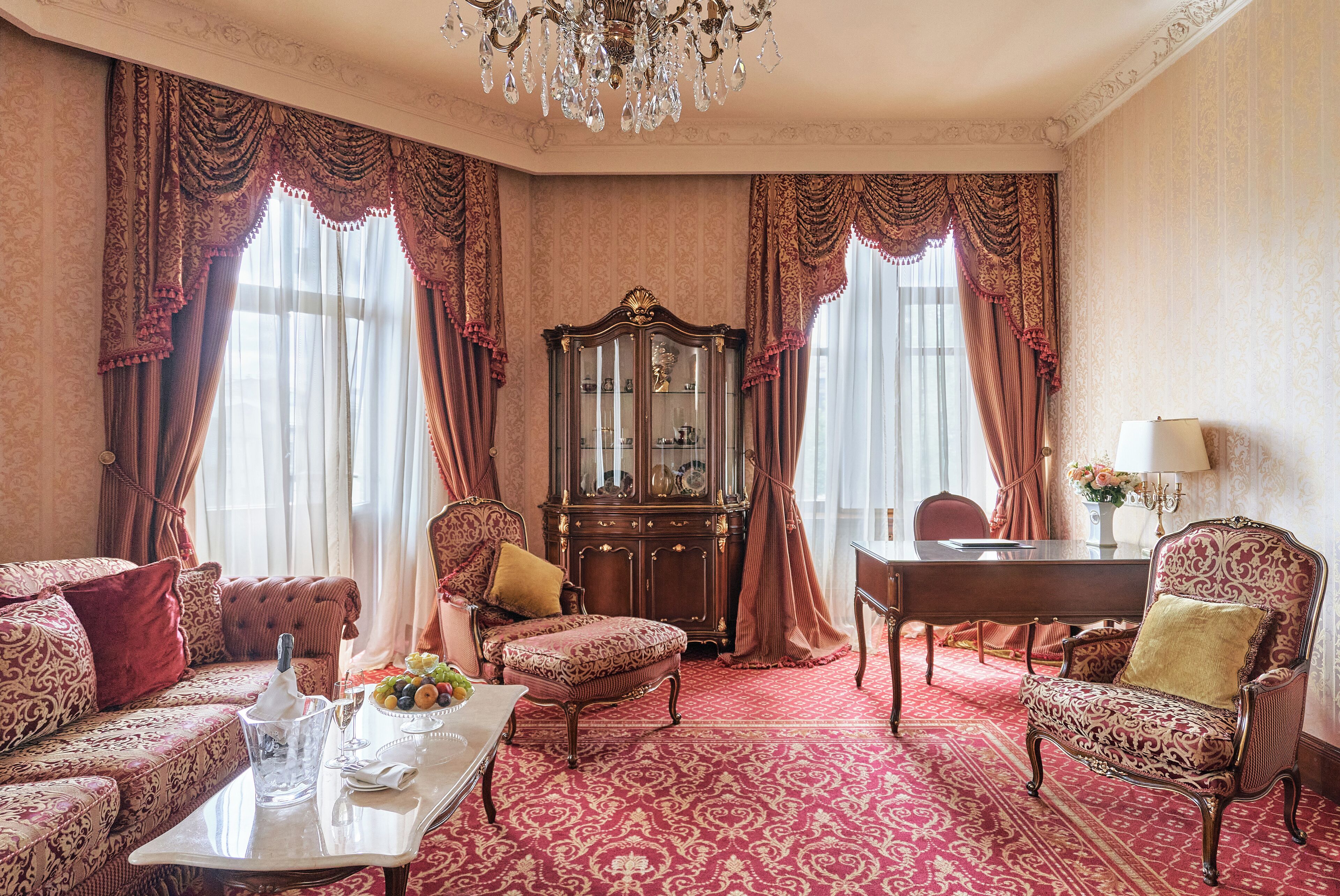 Una habitación con alfombra estampada, un armario de madera, una mesa de comedor y un candelabro.