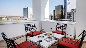 A balcony with a table and chairs, a hat, and sunglasses on the table.