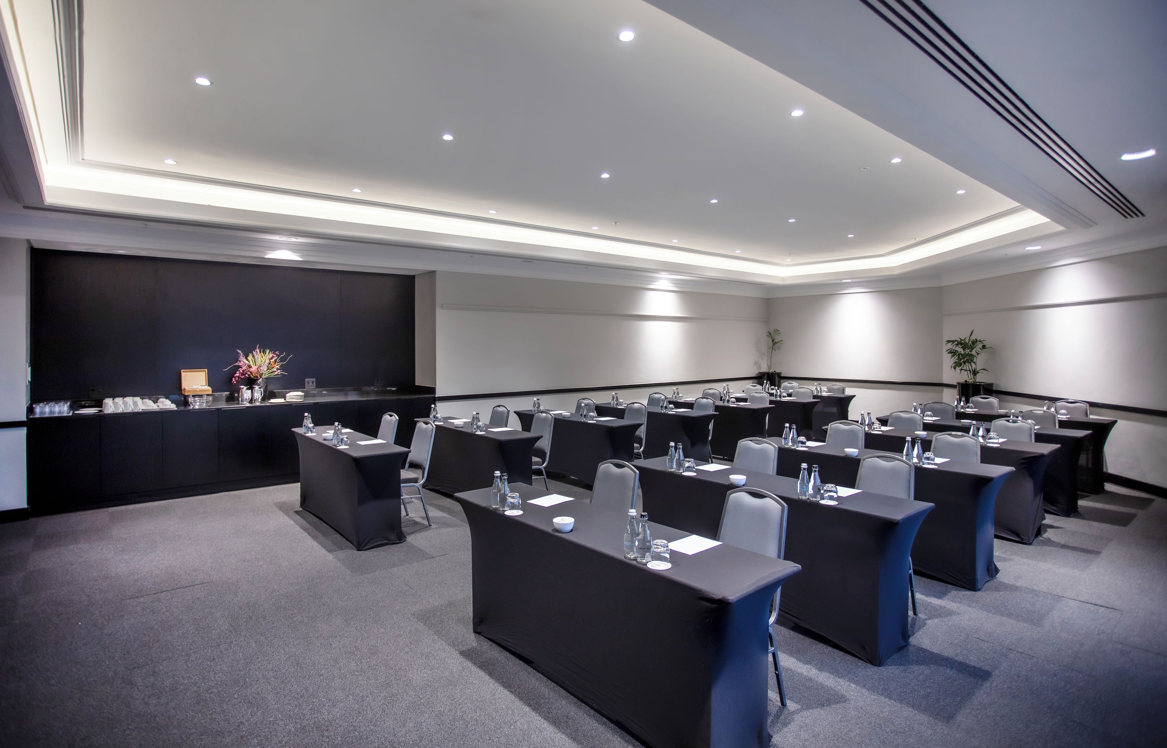 A conference room with multiple tables, chairs, and a stage area with a podium.