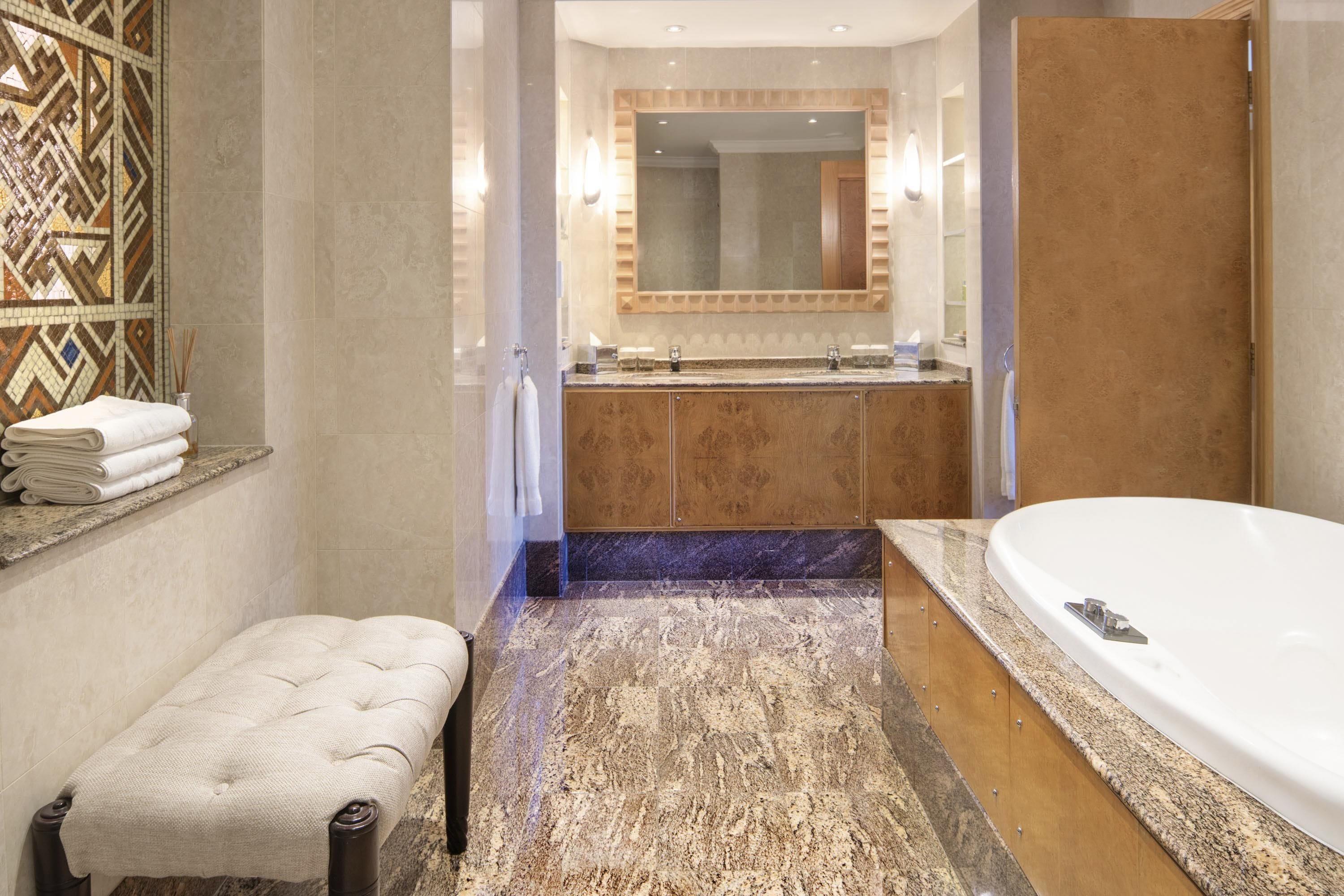 A modern bathroom with a freestanding bathtub, a vanity with a mirror, and a bench.