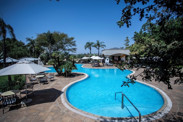 Una piscina al aire libre, sombrillas, sillones reclinables de piscina