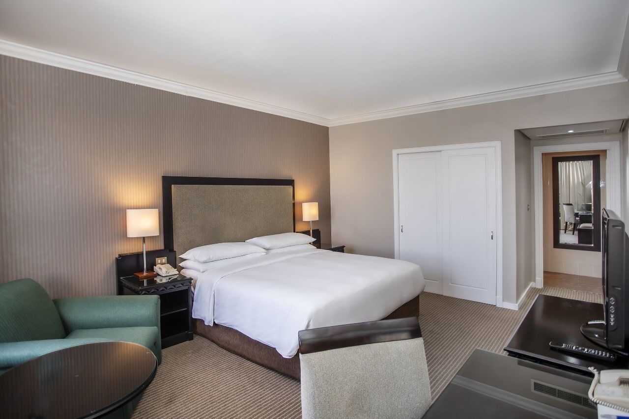 A hotel room with a large bed, a TV, a desk, and a chair.