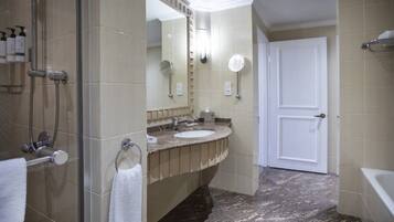 Un baño con cabina de ducha de vidrio, un lavabo con tocador y una puerta blanca.