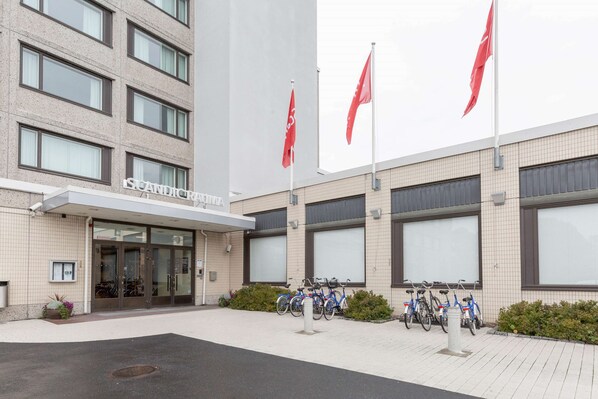 A building with a tiled facade, a glass entrance, and several bicycles parked outside.