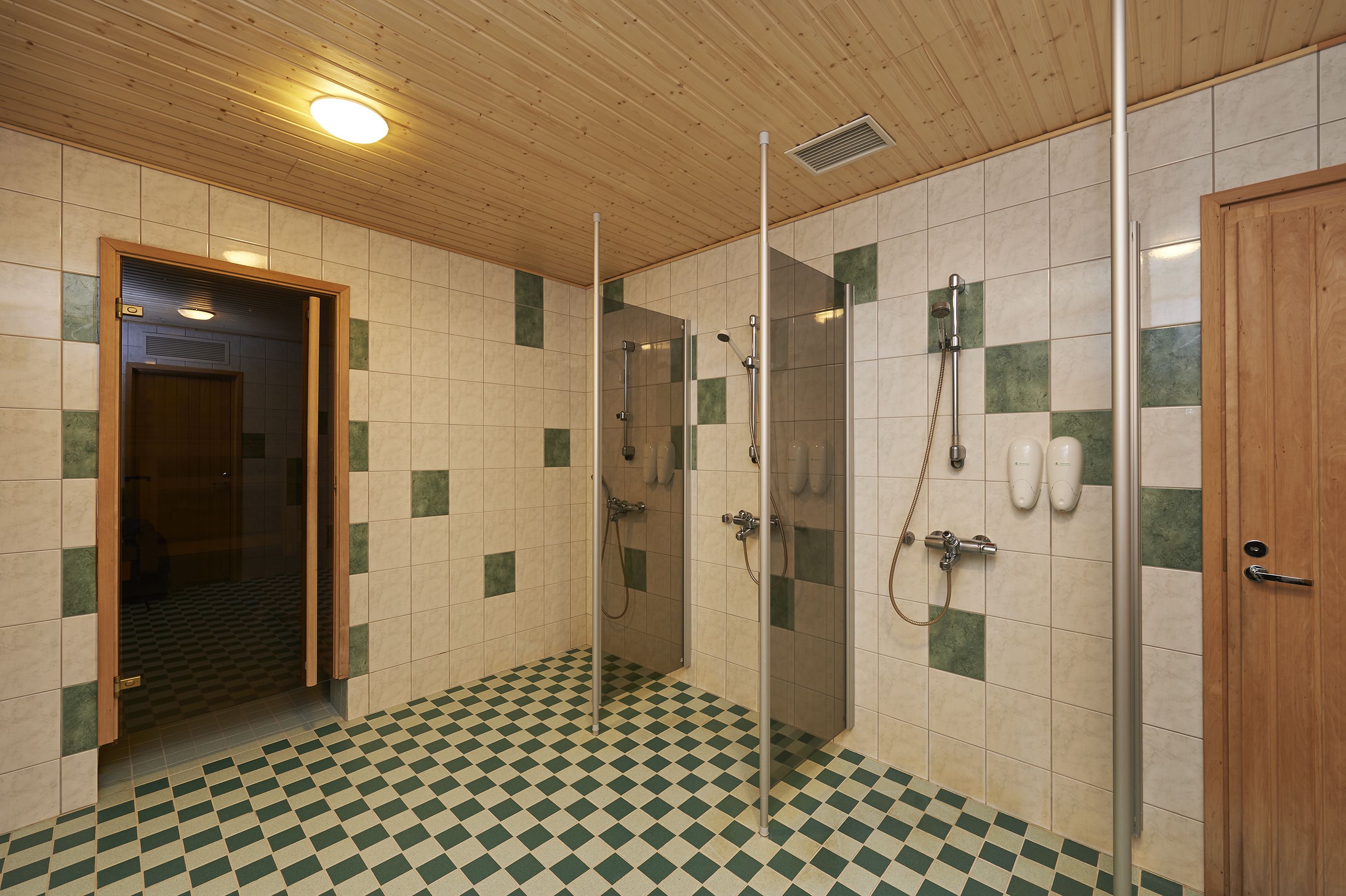 Un baño con piso a cuadros, techo de madera y cabina de ducha de vidrio.