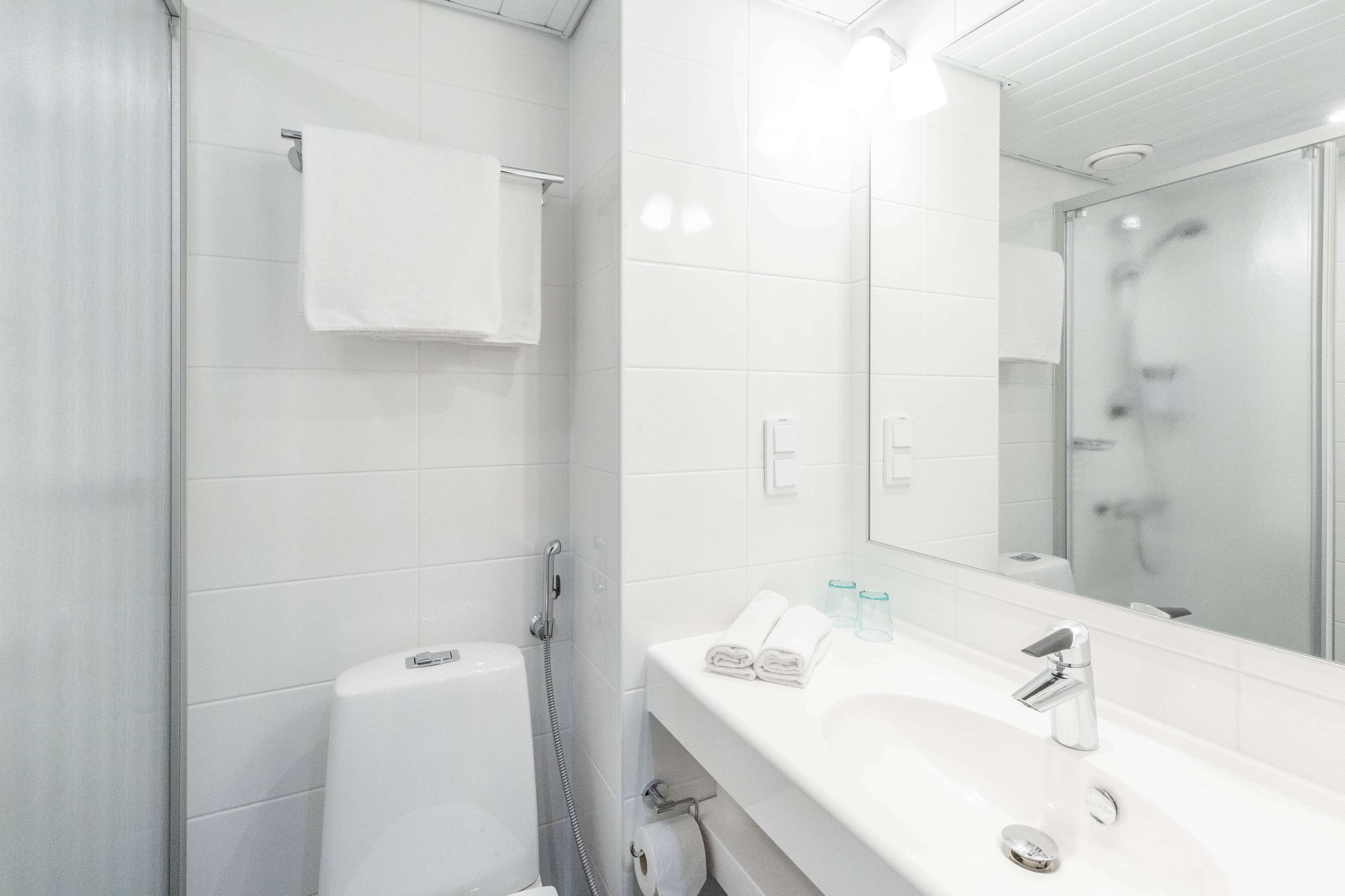A modern bathroom with a white sink, a mirror, and a shower area.