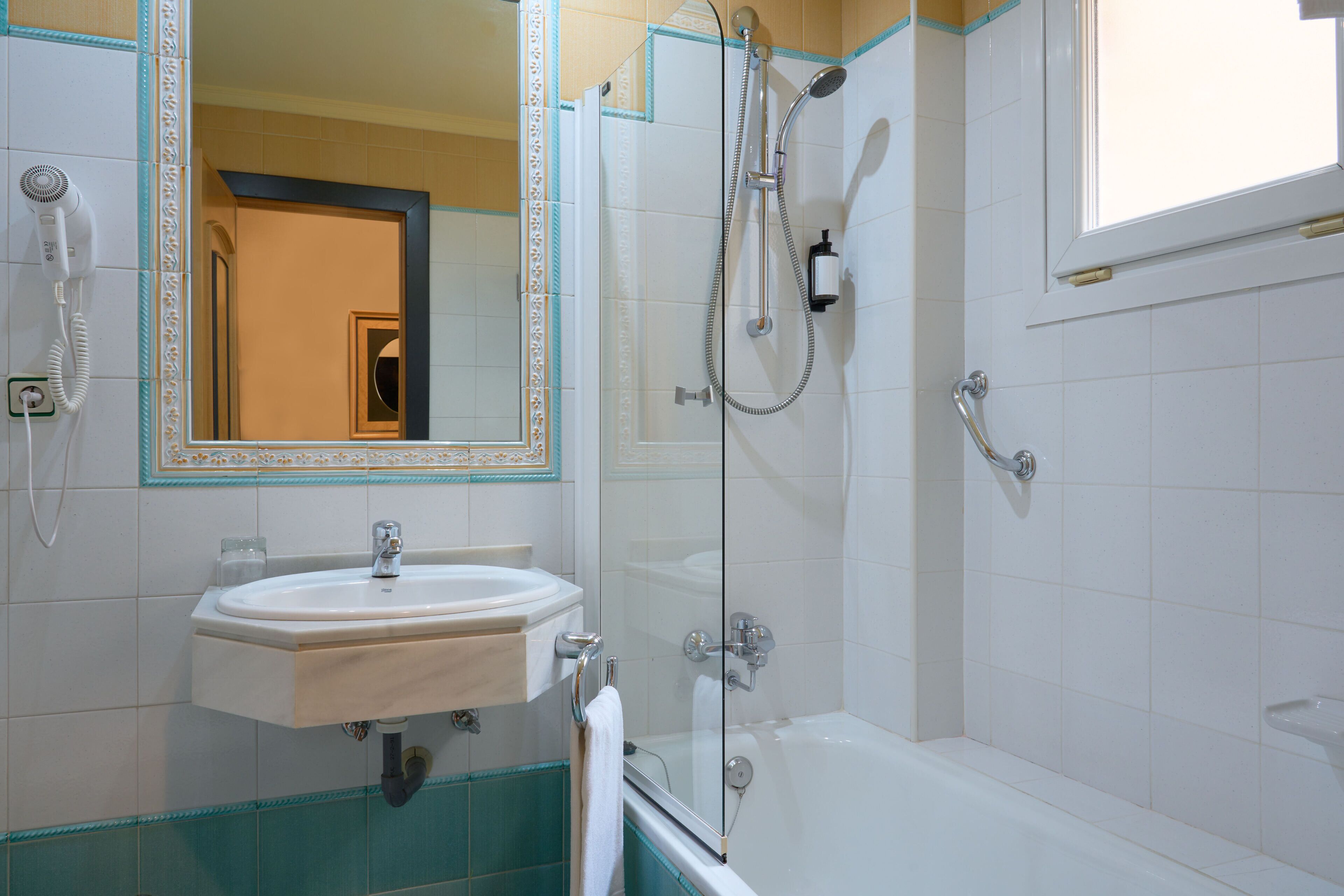 A bathroom with a sink, mirror, shower, and bathtub.
