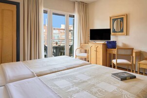 A hotel room with two beds, a TV, a desk, and a chair.