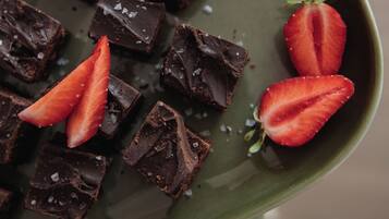 A green plate with chocolate squares and strawberries.