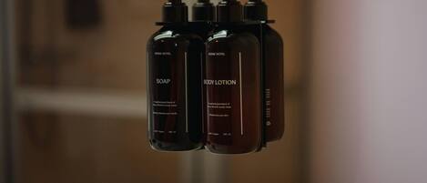 Three bottles of soap and lotion labeled 'HOME HOTEL' on a shelf.