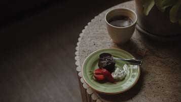 Pieni vihreä lautanen, jonka päällä on suklaajälkiruoka, mansikka ja kermavaahto, ja kaikki tämä on asetettu pitsiliinan päälle.