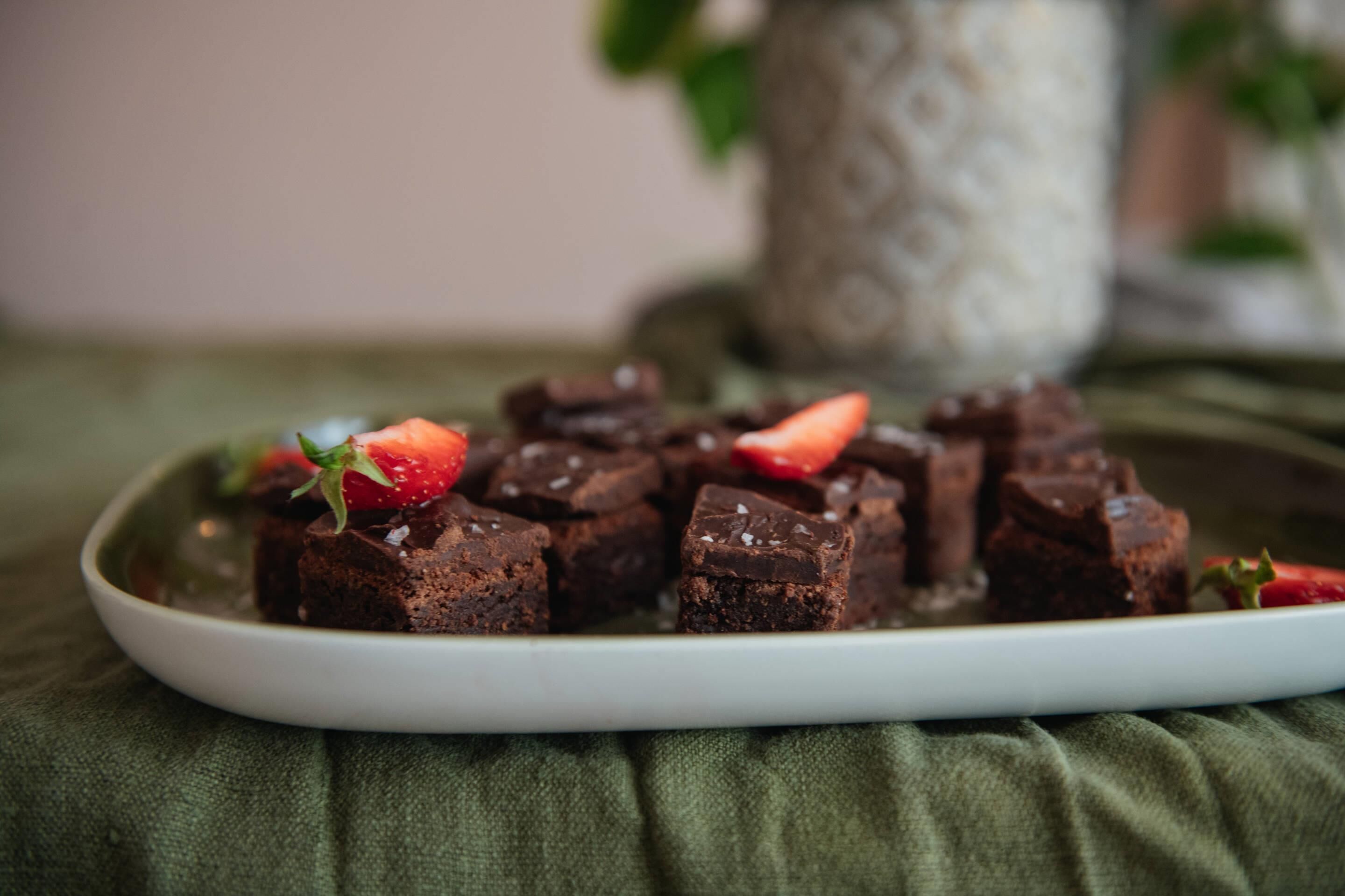 Une assiette de brownies décorée de fraises, le tout posé sur un tissu vert.
