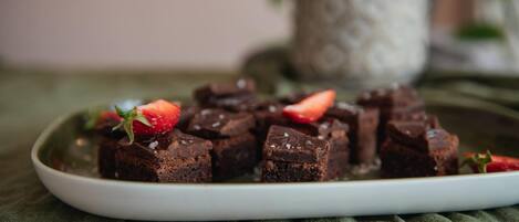Une assiette de brownies décorée de fraises, le tout posé sur un tissu vert.