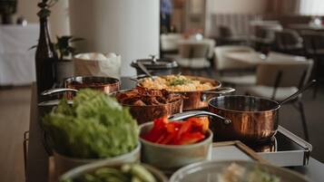 A buffet table with various dishes and a copper pot on a tray.