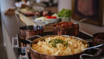 A kitchen counter with various cooking pots and pans, including a large pan of scrambled eggs garnished with herbs.