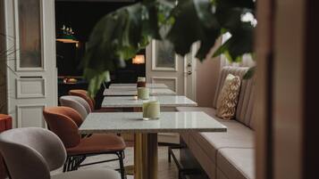 A restaurant with a long counter, cushioned seating, and a large plant in the foreground.