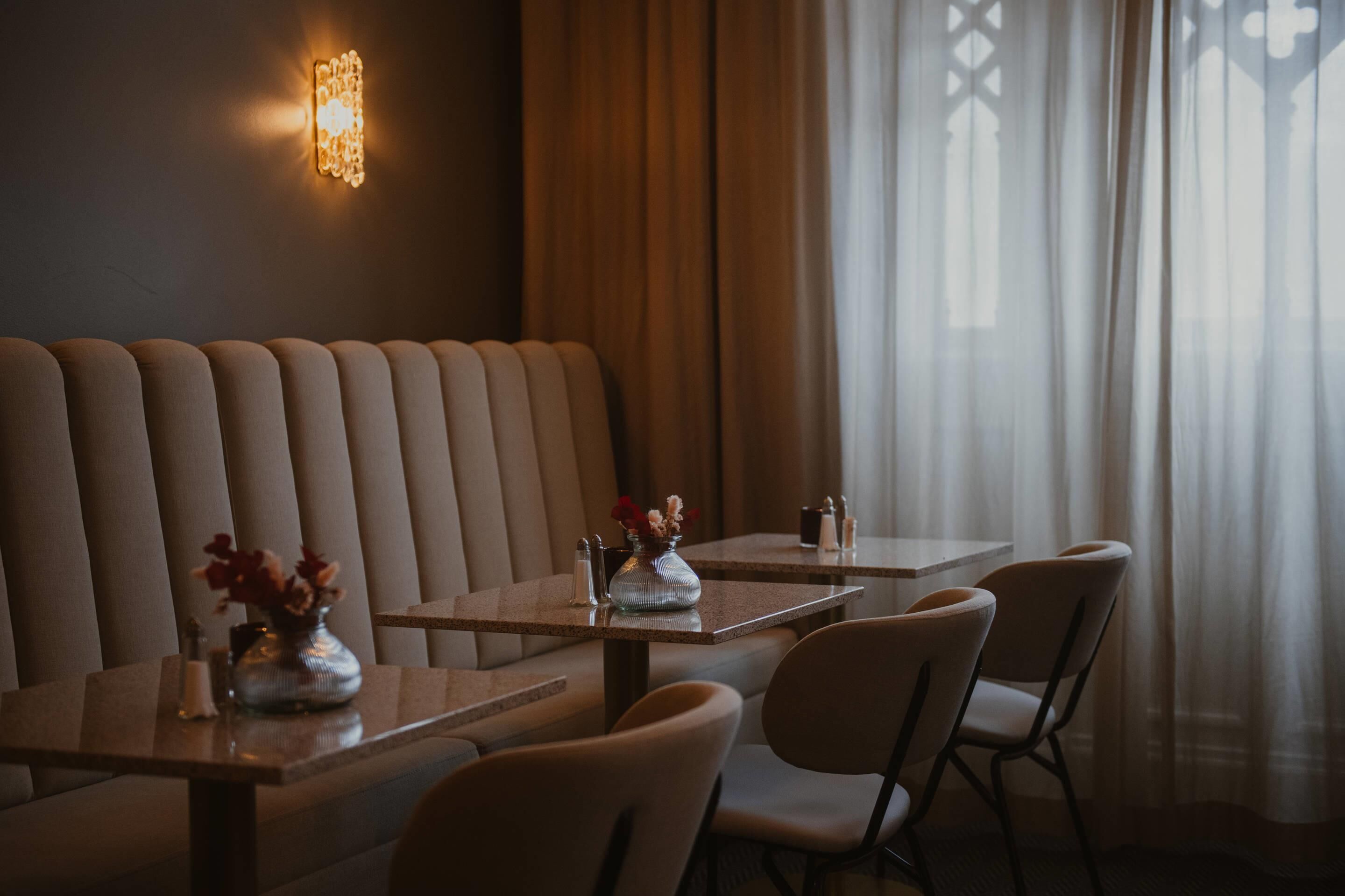 A restaurant with booth seating, tables, and a decorative wall light.